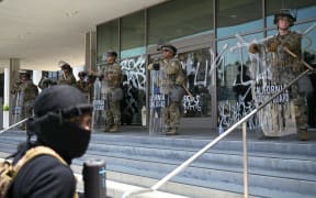 California National Guard members protect the Federal Building, covered in graffiti following protests triggered by immigration raids, in Los Angeles, on June 9, 2025. Police ordered the public to disperse from downtown Los Angeles on June 8 after further unrest, with cars torched and security forces firing tear gas at protesters, in the wake of US President Donald Trump's deployment of National Guard troops to America's second-biggest city. Protests in Los Angeles, home to a large Latino population, broke out on June 6, triggered by immigration raids that resulted in dozens of arrests of what authorities say are illegal migrants and gang members. (Photo by RONALDO SCHEMIDT / AFP)